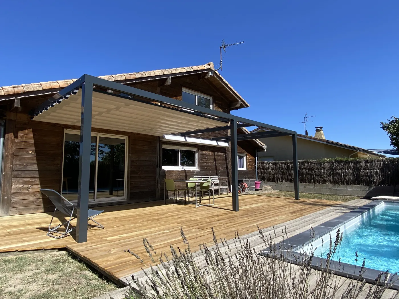 Pergola aluminium au-dessus d'une terrasse en bois, au bord de la piscine